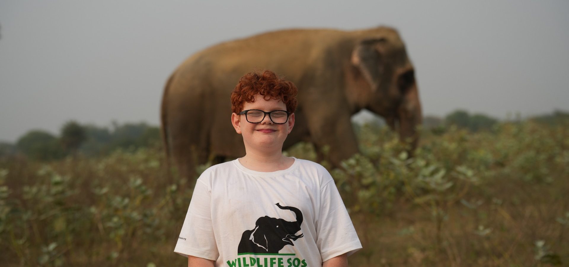 Xavi in the elephant conservation center in India. There is an elephant behind him and is smiling